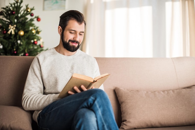 Bel homme lisant un livre à la maison