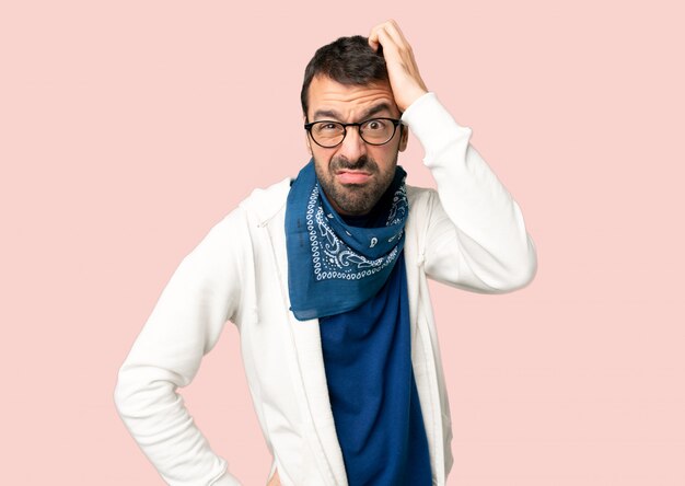 Bel homme avec des lunettes avec une expression de frustration et ne comprenant pas sur fond rose isolé