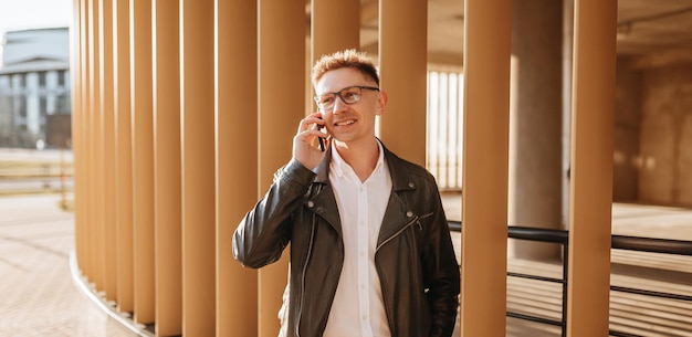 Bel homme avec des lunettes avec un smartphone dans la rue d'une grande ville