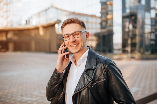 Bel homme avec des lunettes avec un smartphone dans la rue d'une grande ville