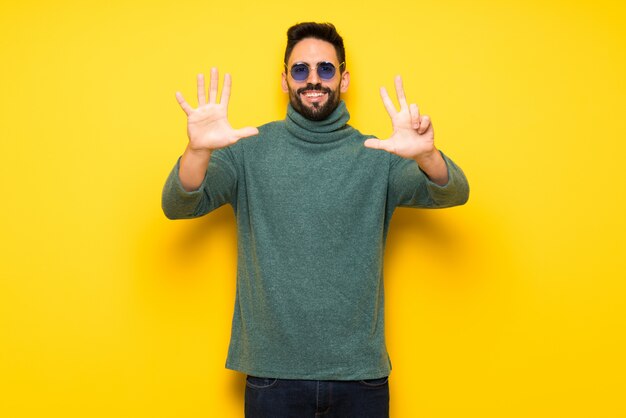 Bel homme avec des lunettes de soleil comptant huit avec les doigts