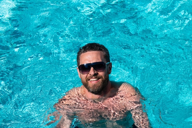 Bel homme à lunettes de soleil. Vacances d'été. Soirée piscine. Station estivale.