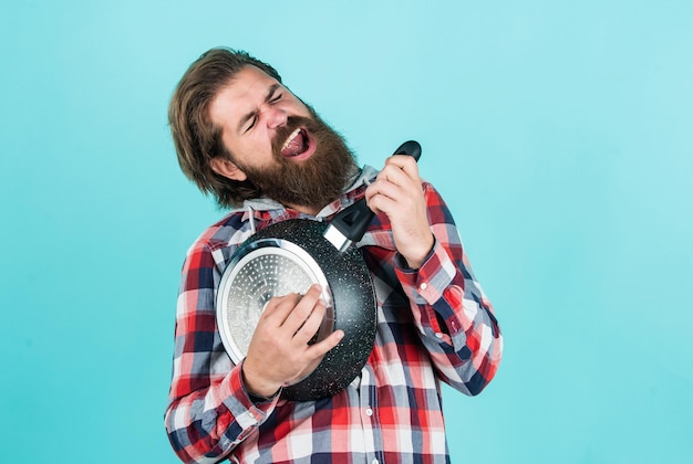 Bel homme mature en chemise à carreaux tenir pan pour la cuisson des aliments, cuisine.