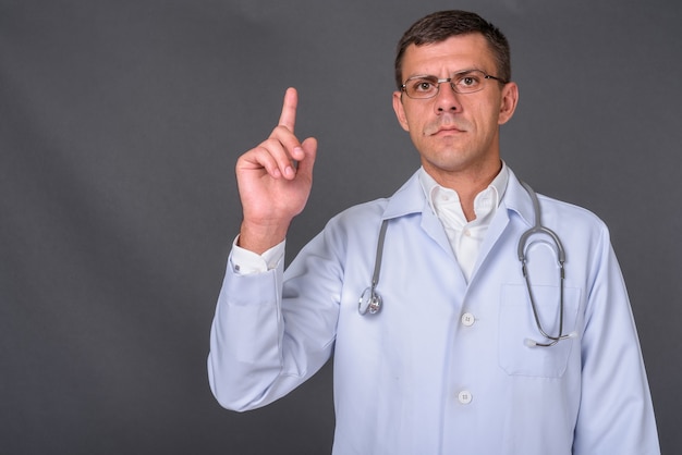 Photo bel homme médecin aux cheveux courts sur fond gris