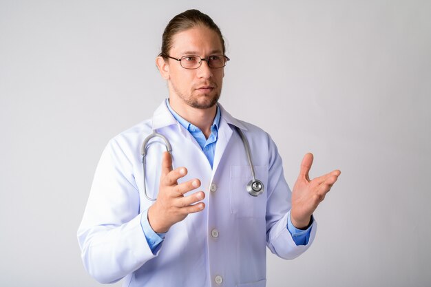 Bel homme médecin portant des lunettes contre le mur blanc