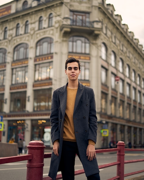 Bel homme à la mode élégant, brune en élégant manteau gris, se dresse sur la rue