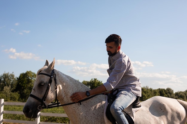 Le bel homme monte à cheval dans un ranch