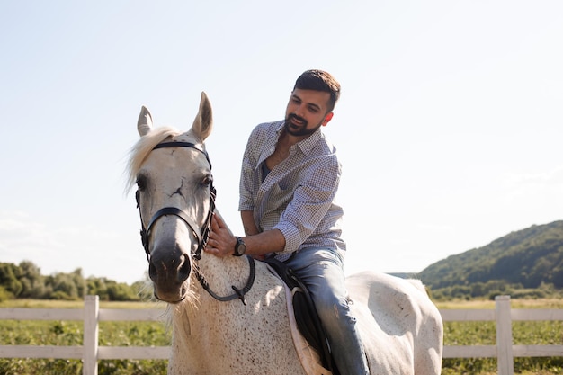 Le bel homme monte à cheval dans un ranch