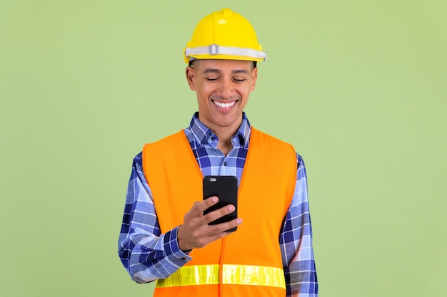 Bel homme multiethnique travailleur de la construction contre un mur de couleur