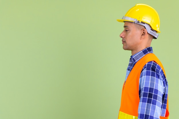 Bel homme multiethnique travailleur de la construction contre un mur de couleur