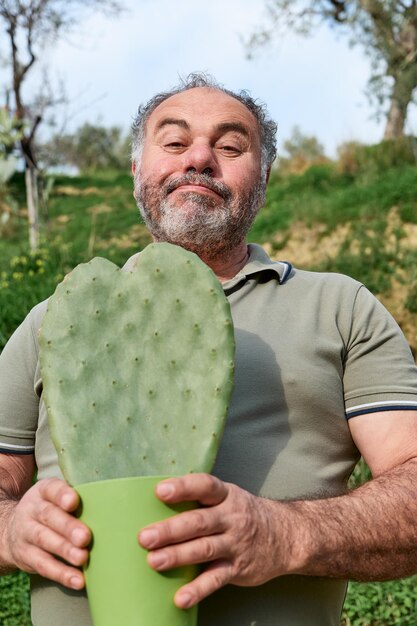 Bel homme mûr barbu tient un cactus en forme de coeur dans le pot