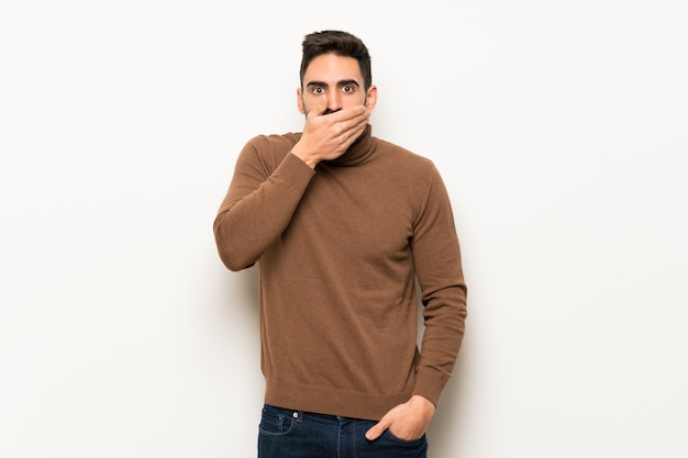 Bel homme sur un mur blanc couvrant la bouche avec les mains pour avoir dit quelque chose d&#39;inapproprié