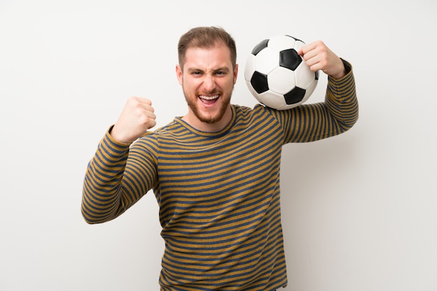 Bel homme sur mur blanc isolé, tenant un ballon de foot