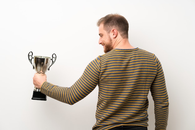 Bel Homme Sur Un Mur Blanc Isolé, Tenant Un Trophée