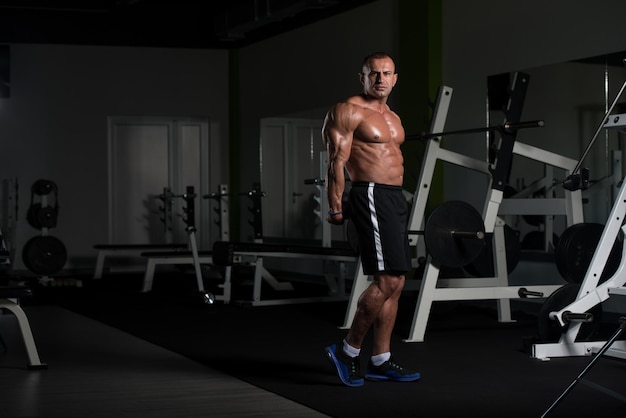 Bel homme mûr debout fort dans la salle de gym et muscles de la flexion musclé athlétique Bodybuilder Fitness mâle posant après les exercices