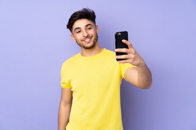 Bel homme sur un mur isolé faisant un selfie