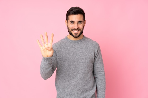 Bel homme sur mur isolé heureux et comptant quatre avec les doigts