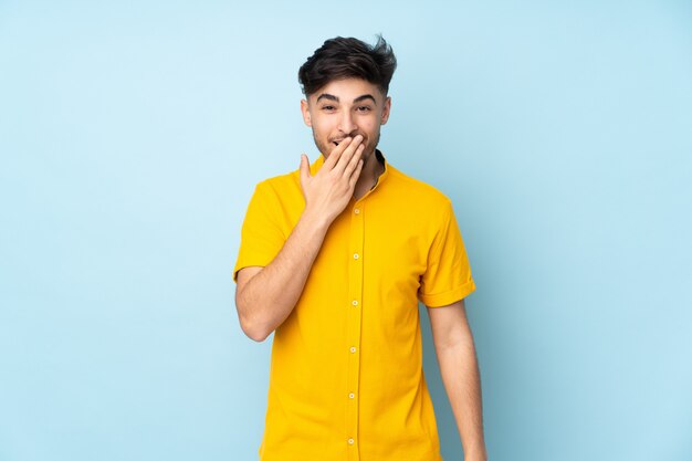 Bel homme sur mur isolé heureux et souriant couvrant la bouche avec la main