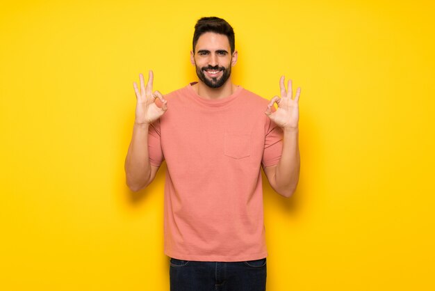 Bel homme sur un mur jaune en pose zen