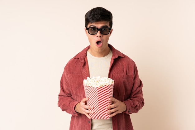 Bel homme sur mur surpris avec des lunettes 3d et tenant un grand seau de pop-corn