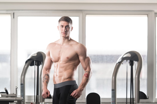 Bel homme musclé flexion des muscles dans la salle de gym