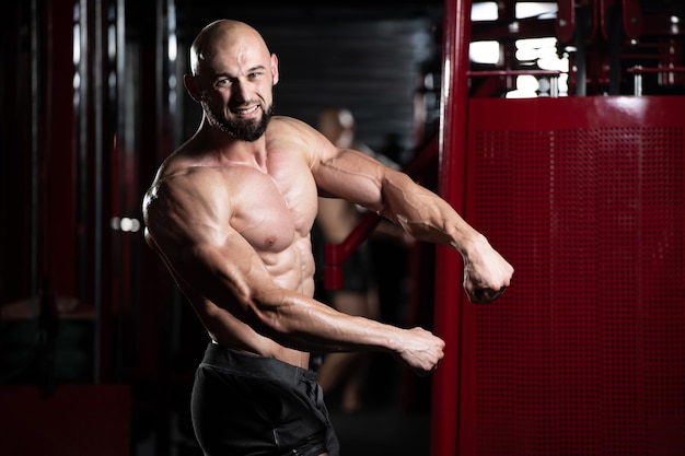 Bel homme musclé flexion des muscles dans la salle de gym