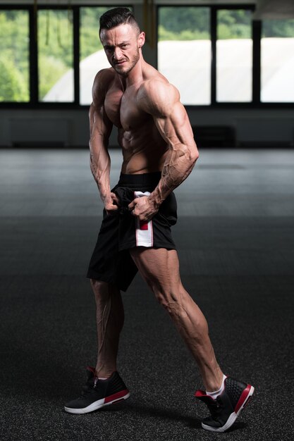 Bel homme musclé flexion des muscles dans la salle de gym