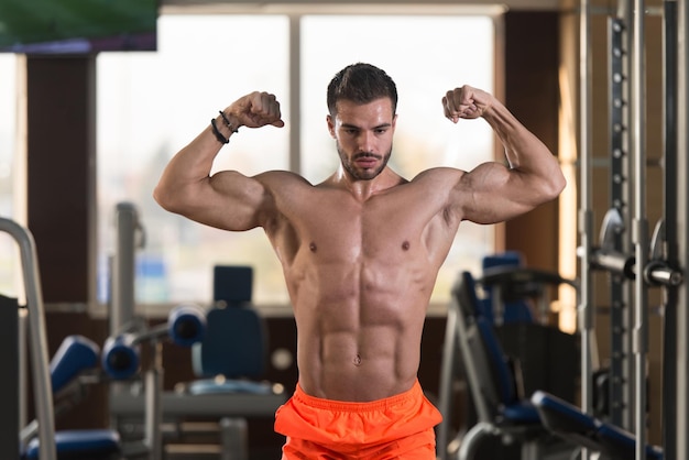 Bel homme musclé flexion des muscles dans la salle de gym