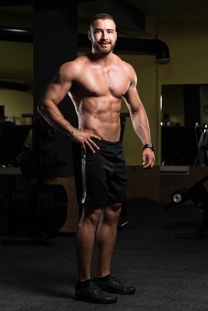 Bel homme musclé flexion des muscles dans la salle de gym