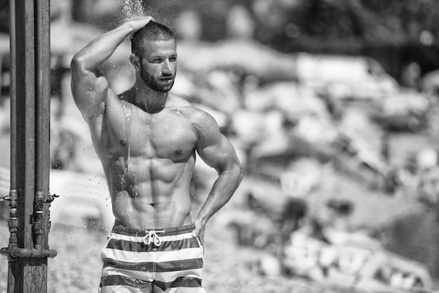 Photo un bel homme musclé prend une douche à l'extérieur