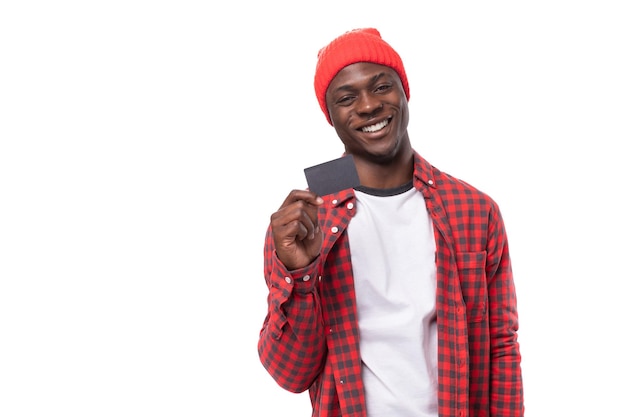 Bel homme noir dans un style décontracté montrant une maquette de carte de crédit avec la main sur fond blanc avec