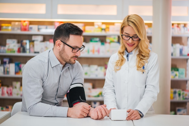 Bel homme obtenant sa tension artérielle dans un magasin de produits pharmaceutiques.