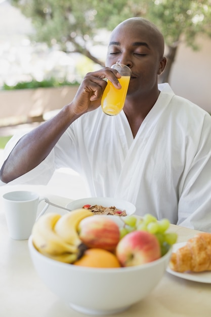 Bel homme en peignoir prenant son petit déjeuner à l&#39;extérieur