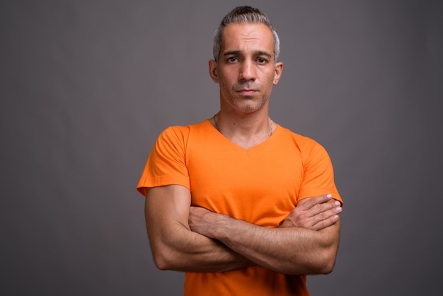 Bel homme persan aux cheveux gris portant un t-shirt orange