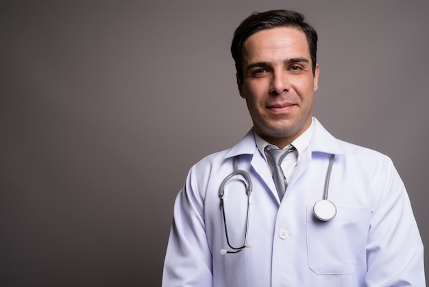 Bel homme persan médecin contre le mur gris