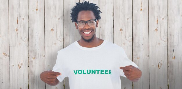 Photo bel homme pointant vers son t-shirt bénévole sur fond de bois