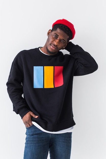 Bel homme posant en sweat-shirt noir sur un mur blanc