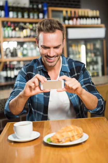 Bel homme prenant une photo de son sandwich