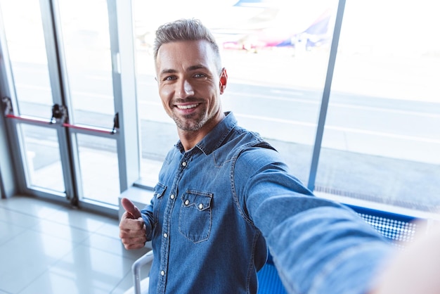 Bel homme prenant selfie à l'aéroport