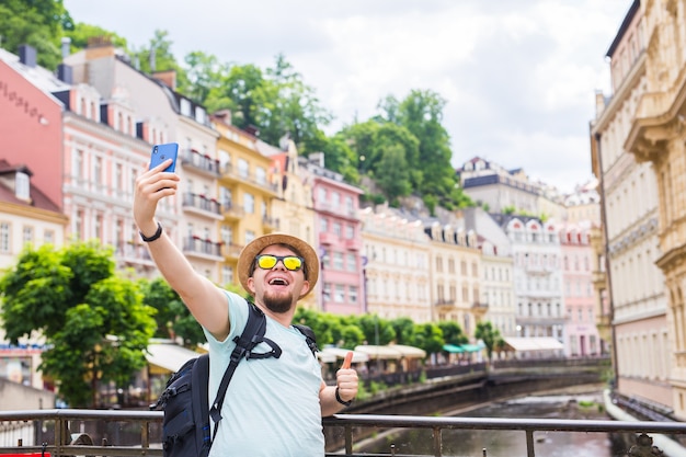 Photo bel homme prenant selfie avec appareil photo de téléphone intelligent mobile dans la ville européenne.