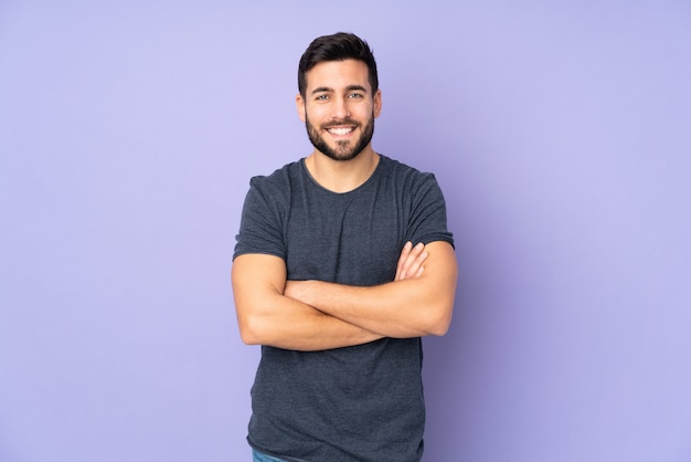 Bel homme de race blanche en gardant les bras croisés en position frontale sur mur violet isolé