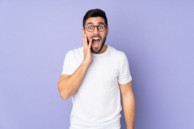 Bel homme de race blanche sur un mur isolé avec surprise et expression faciale choquée