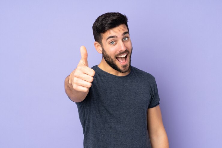 Photo bel homme de race blanche avec les pouces vers le haut parce que quelque chose de bien s'est produit sur le mur violet