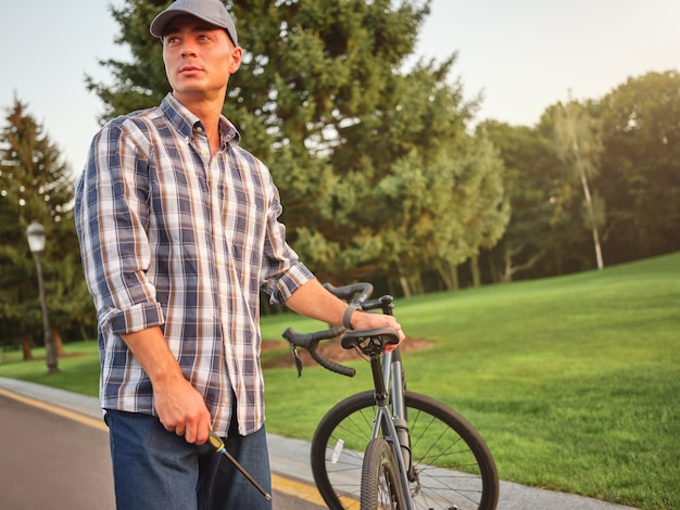 Bel homme de race blanche regardant loin tenant un tournevis pour réparer son vélo debout dans le