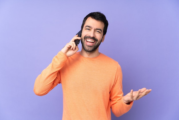 Bel homme de race blanche sur violet isolé, garder une conversation avec le téléphone mobile avec quelqu'un