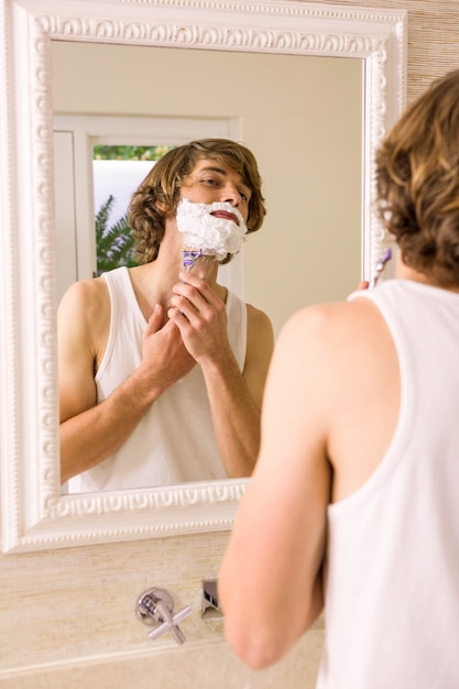 Bel homme rasage dans la salle de bain à la maison