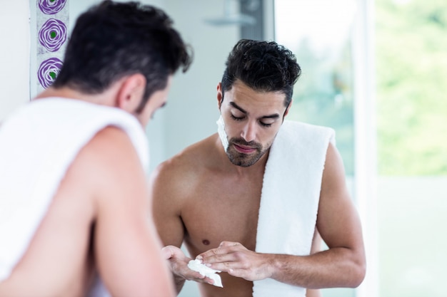 Bel homme rasant sa barbe dans la salle de bain