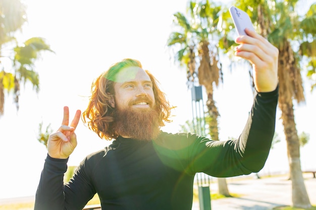 Bel homme redhaireb avec une longue barbe porter un costume sportif noir et se réchauffer sur une plage ensoleillée