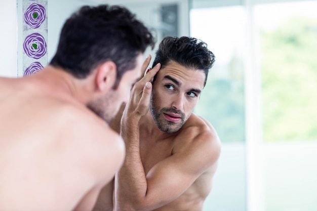 Bel homme regardant ses cheveux dans la salle de bain