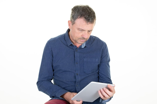 Bel homme regarde en lisant son ordinateur tablette à écran tactile numérique